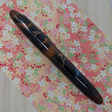 Load image into Gallery viewer, Back view of the fountain pen, laid on a print with flowers.