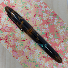 Load image into Gallery viewer, Side view of the fountain pen laid on a print with flowers.
