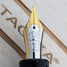 Load image into Gallery viewer, Front view of the bi-colored fountain pen nib with engravings: The Taccia logo, 18K, 750, JAPAN