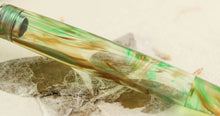Load image into Gallery viewer, Close up to the demonstrator fountain pen barrel. It features green and light brown swirls.