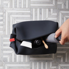 Load image into Gallery viewer, Top view of the black bag being filled with toiletries.