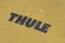 Load image into Gallery viewer, Close up to the Thule logo with water drops around it, showing its waterproof feature.