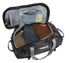 Load image into Gallery viewer, Interior view of the black duffle bag with clothes and accessories arranged inside.