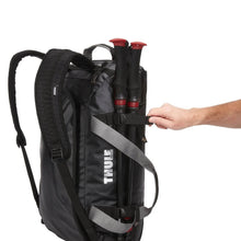 Load image into Gallery viewer, Side panel view of the duffel bag with hiking gear attached with a set of adjustable straps.