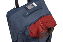 Load image into Gallery viewer, Angled top panel view of the dress blue duffle bag with a red jacket peeking from a pocket.