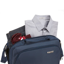 Load image into Gallery viewer, A set of folded clothes being tucked into the main compartment.