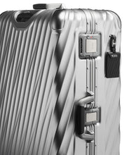Load image into Gallery viewer, Angled close up to the side panel of the suitcase. It features a black tag, a grab handle, and locking clasps. The top clasp has a TSA approved three-digit combination lock.
