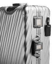 Load image into Gallery viewer, Angled close up to the suitcase's side panel. It shows a black tag, a grab handle and locking clasps. The one at the top features a TSA approved three-digit combination.