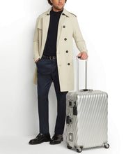 Load image into Gallery viewer, A young man wearing a beige trench coat holding his suitcase by the telescopic handle.