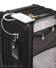 Load image into Gallery viewer, Angled close up to the suitcase showing the phone connected to a USB plug