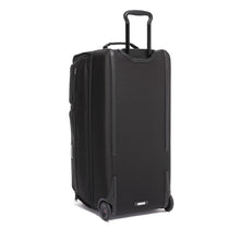 Load image into Gallery viewer, Angled back panel view of the black wheeled duffle bag with the telescopic handle extended.
