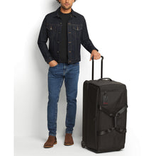 Load image into Gallery viewer, A young man holding the duffle bag by the extended telescopic handle.