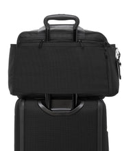 Load image into Gallery viewer, Back panel view of the duffle placed on top of a suitcase. The telescopic handle is passed through the back strap to keep the it in place.