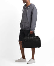 Load image into Gallery viewer, A young man holding the duffel by the handles.