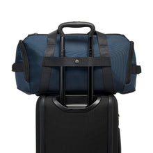 Load image into Gallery viewer, Back panel view of the navy blue suitcase with the back strap shown attached to a suitcase's telescopic handle.