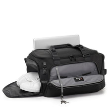 Load image into Gallery viewer, Angled front panel view of the black duffel bag with the front panel, and side shoe compartments unzipped. The front pocket has a key leash, and the back panel a pocket for a small laptop.