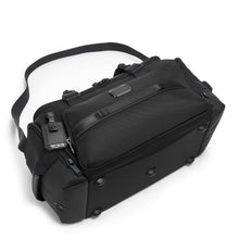 Load image into Gallery viewer, The black duffel laid on its back panel, showing the five short stub legs at the bottom panel to keep the bag clean.