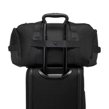 Load image into Gallery viewer, Back panel view of the black suitcase with the back strap shown attached to a suitcase's telescopic handle.