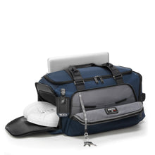 Load image into Gallery viewer, Angled front panel view of the navy blue duffel bag with the front panel, and side shoe compartments unzipped. The front pocket has a key leash, and the back panel a pocket for a small laptop.