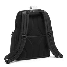 Load image into Gallery viewer, Angled back panel view of the black backpack, showing a set of adjustable straps and a cellphone peeking from a pocket under the grab handle.