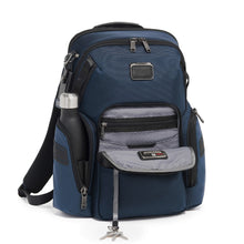 Load image into Gallery viewer, Angled front panel view of the backpack with a water bottle peeking from the side pocket (bottle not included). The front pocket is unzipped and features a cord to clip your keys.