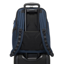 Load image into Gallery viewer, Back panel view of the blue backpack showing the attachment strap. The telescopic handle of a suitcase is passed through it to hold the backpack in place.