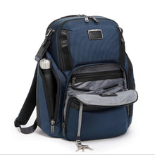 Load image into Gallery viewer, Angled front panel view of the blue backpack with the front and side pocket unzipped. The side pocket has a water bottle peeking through it, and a the front pocket features a long string with a key ring.
