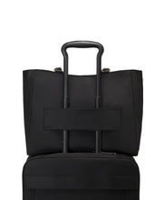 Load image into Gallery viewer, Back panel view of the bag with the telescopic handle of a suitcase passing through the attachment strap to hold the bag in place.