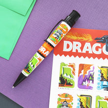 Load image into Gallery viewer, Side view of the pen laid on a card with cartoon dragons on post stamps.