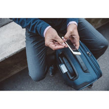 Load image into Gallery viewer, Top view of the suitcase placed in front of a man, while he sits holding his cellphone.