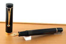 Load image into Gallery viewer, The fountain pen with the cap set to the side. Placed on top of the wooden presentation box.