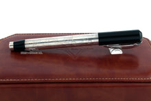 Load image into Gallery viewer, Side view of the fountain pen with the cap on, closed. Laid on top of the brown leather presentation box.