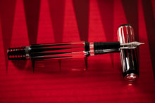 Load image into Gallery viewer, The Visconti Backgammon Fountain Pen with the nib resting on the cap. Laid on a red backgammon board.