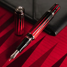Load image into Gallery viewer, The Visconti Backgammon Fountain Pen with the cap set behind it. It is laid on a red background and leaning on a black leather letter pad.
