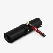 Load image into Gallery viewer, The Visconti Backgammon Rollerball pen leaning on its rolled leather case.