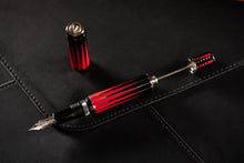 Load image into Gallery viewer, Angled view of the Visconti Backgammon Fountain Pen. The cap set next to it, and the piston lever is pulled.