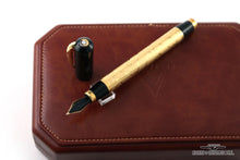 Load image into Gallery viewer, Back view of the fountain pen with the cap set next to it. The top of the cap is visible with a golden medal and a diamond at the center.