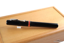 Load image into Gallery viewer, Side view of the fountain pen with the cap, closed. Placed on top of the wooden presentation box.