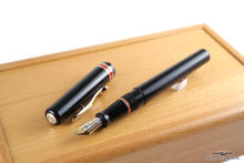 Load image into Gallery viewer, The Fountain pen with the cap set to the side. Placed on top of the wooden presentation box.