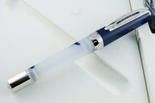 Load image into Gallery viewer, Angled front view of the pen. It has a small card under the nib with details of the pen's materials.