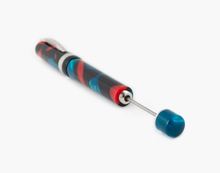 Load image into Gallery viewer, Angled close up to the Visconti Woodstock in Dark Lava Lamp Fountain pen. The piston lever is pulled. The pen body is made of red, black, and blue acrylic resin swirls with metal fittings.
