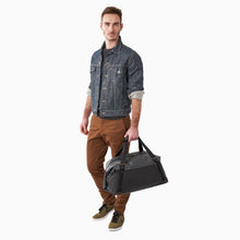Load image into Gallery viewer, Briggs & Riley ZDX Cargo Crossbody Satchel - Black
Image of male model carrying Crossbody Satchel by handles.
	Height	Width	Depth	Weight
US	13.25"	22.25"	12"	          2.1 lbs.
EU	33.8 cm	30.5 cm	56.6 cm	 .9 kg