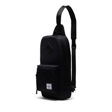 Load image into Gallery viewer, Angled view of the black sling bag with the shoulder strap extended up.
