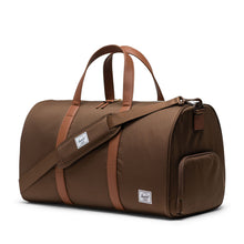 Load image into Gallery viewer, Angled front view of the dark earth brown duffle bag. The matching adjustable shoulder strap is laid across it.
