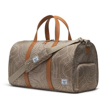 Load image into Gallery viewer, Angled front view of the light brown duffle bag with topography print. The shoulder strap is placed across it.
