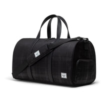 Load image into Gallery viewer, Angled front view of the black Plaid Embossed duffle bag with the adjustable shoulder strap across.

