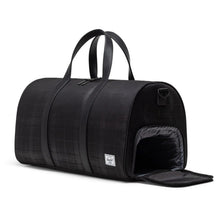 Load image into Gallery viewer, Angled view of the black plaid embossed duffle bag with the side panel shoe compartment opened.
