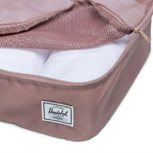 Load image into Gallery viewer, Close up to a rose pink packing cube with clothes rolled inside.
