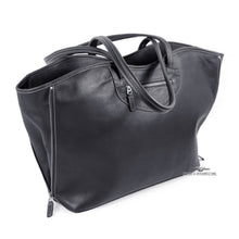 Load image into Gallery viewer, Angled front view of the black tote bag. The shoulder straps are resting across the top. 
