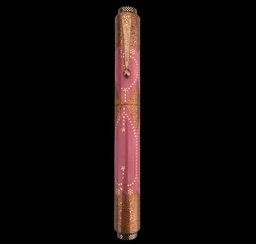 Decorative pen with pink and gold design on a black background.